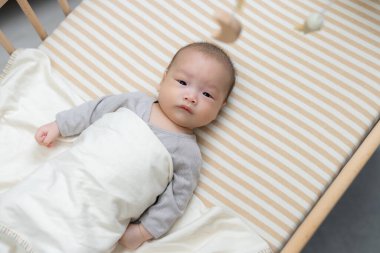 Sevimli bebek rahatlıyor ve beşik oyuncağının tadını çıkarıyor.