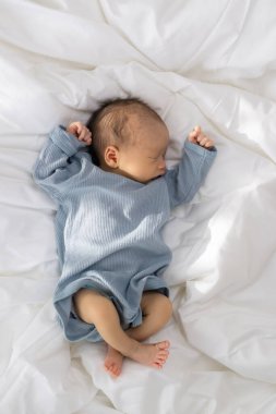 Yeni doğmuş bebek yumuşak yatakta huzur içinde uyuyor.