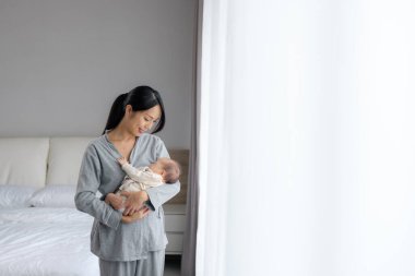 Anne bebeği kucağında tutuyor.