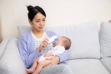 Anne, bebek sıcaklığını ölçüyor. 