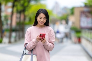 Gündüz dışarıda cep telefonu kullanan bir kadın