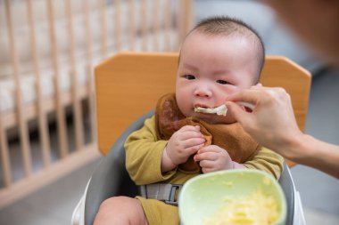 Bebek ilk katı yemeğin tadını çıkarıyor.