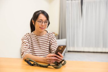 Evde cep telefonu kullanan bir kadın.