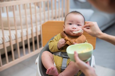 Bebek yüksek sandalyede yumuşak yemek yiyor.