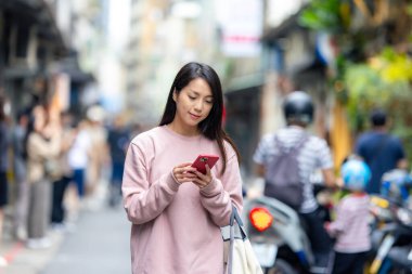 Genç bir kadın gün ışığında cep telefonunu kontrol ediyor.