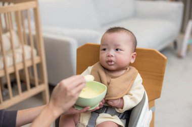 Bebek yüksek sandalyede yemek yiyor.