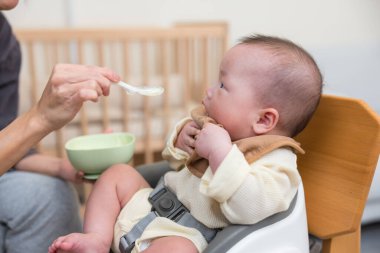 Bebek ahşap sandalyede yemeğin tadını çıkarıyor