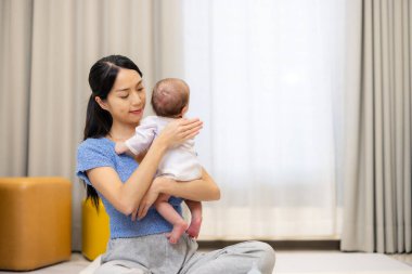 Kadın, beslendikten sonra geğirmesi için bebeğe bakıyor.