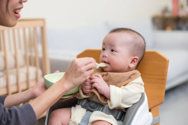 Bebek annesinin yardımıyla yemek yiyor.