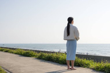 Genç bayan huzurlu deniz manzarasının tadını çıkarıyor.