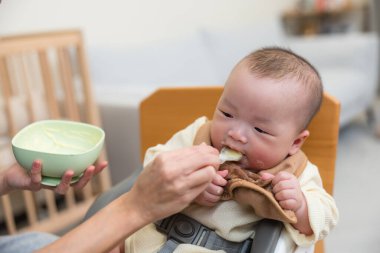 Gülümseyen bebek yüksek sandalyede yemek yiyor.