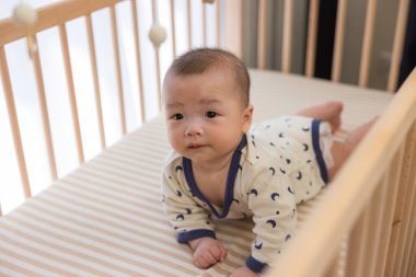 Bebek beşiğinde sürünen tatlı bir erkek bebek.