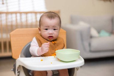 Küçük bebek evde taze havucun tadını çıkarıyor.