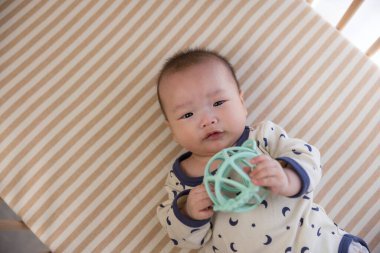 Beşikteki oyuncağa uzanan küçük bebek