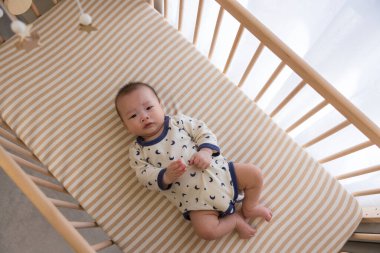 Küçük bebek mutlu bir şekilde tahta beşiğinde yatıyor.