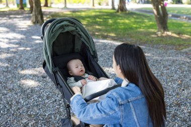 Anne dışarıda bebek arabasında bebekle konuşuyor.