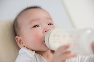 Bebek, ebeveyn eliyle şişeden içiyor.