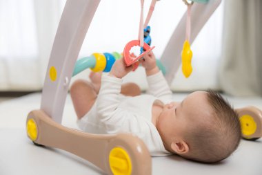 Bebekler spor salonunda asılı oyuncaklarla oynuyor.