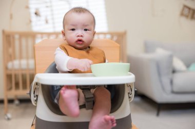 Yemek sandalyesinde duran sevimli bebek.