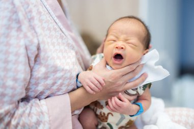 Anne bebeği nazikçe kollarında tutuyor.