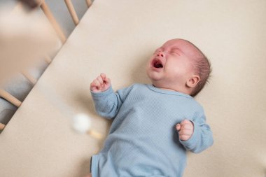 Ağlayan yeni doğmuş bebek beşiğinde yatıyor