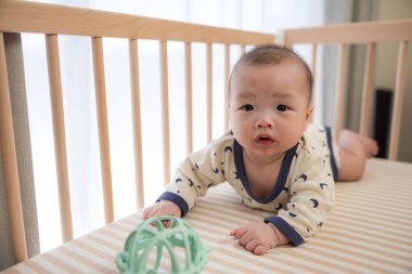 Bebek top oynayıp yatakta sürünüyor.