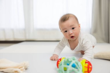 Bebek yerde sürünüyor oyuncağa uzanıyor