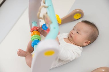 Küçük bebek renkli asılı oyuncaklara uzanıyor