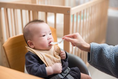 Anne, bebeğin ilk kaşığı yemesine yardım ediyor.