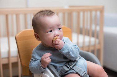 Otururken yemek tutan küçük bebek