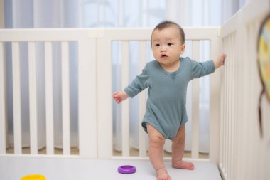 Tahta beşiğin içinde tek başına duran meraklı bebek.