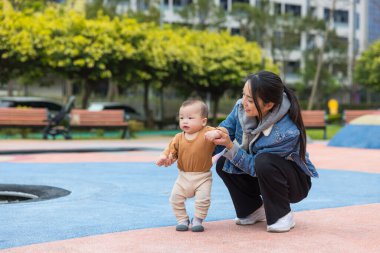 Anne bebeğe dışarıda yürümeyi öğretiyor.