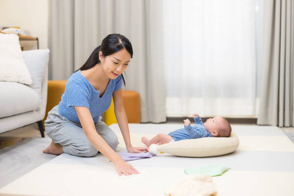 Mother cleaning floor while baby resting
