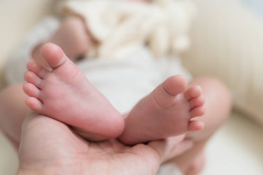 Yeni doğmuş bebek ayakları nazikçe ebeveyn tarafından tutulur.