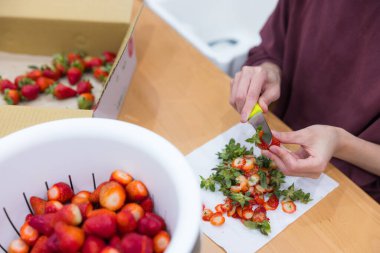 Masadaki taze çilekleri buduyor.