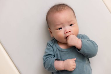 Yeni doğmuş bebek evde dinlenirken parmak emiyor.