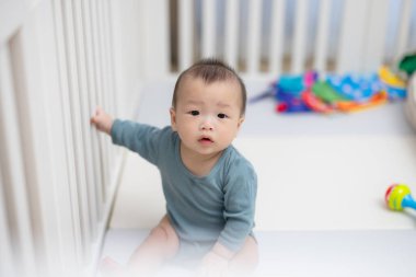 Beyaz karyolada oturan tatlı bebek