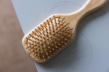 Düşmüş saç telleri, ahşap tarak ve saç fırçası.