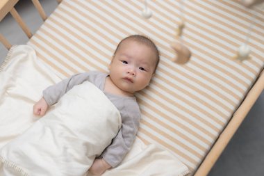 Beşikteki asılı oyuncağa bakan meraklı bebek