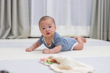 Sevimli yeni doğmuş bebek paspasın üzerinde emeklemeyi öğreniyor.