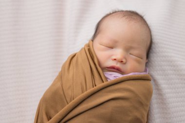 Paketlenmiş yeni doğmuş bebek yumuşak yüzeyde uyuyor