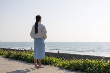 Kadın tek başına okyanusa bakıyor.
