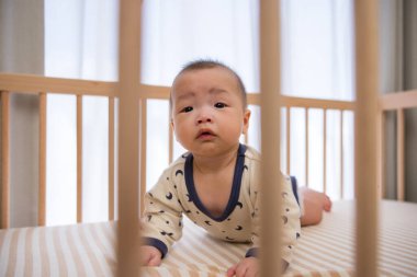 Tahta beşiğin içinde güvenli bir şekilde sürünen tatlı bebek.