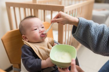 Gülümseyen bebek evde yemeğin tadını çıkarıyor.