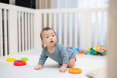 Beyaz karyolada yumuşak oyun paspasında sürünen tatlı bebek.