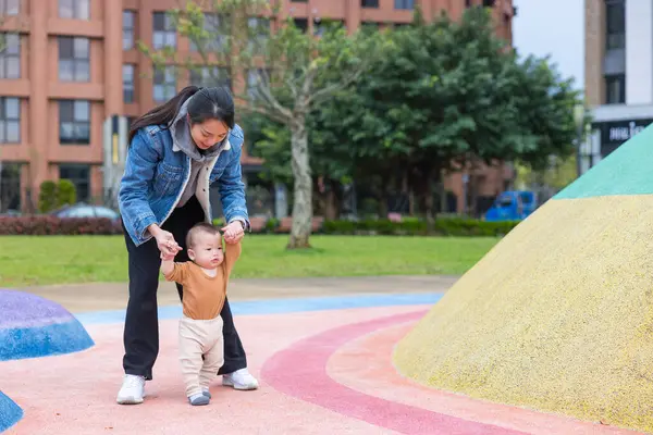 Anne bebeğe dışarıda yürümeyi öğretiyor.
