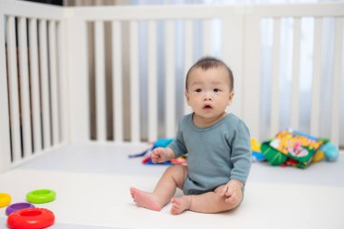 Bebek beşikte oturuyor oyuncaklarla çevrili