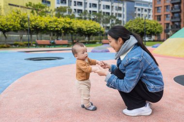 Annesiyle ilk adımı atan bebek yardım eder.