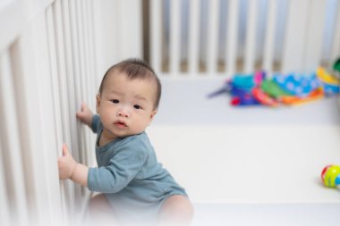 Bebek beşikte oturuyor oyuncaklarla çevrili