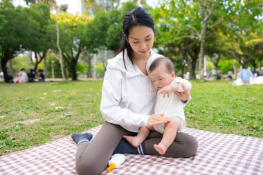 Anne oğlunu parkta güneş kremiyle koruyor.